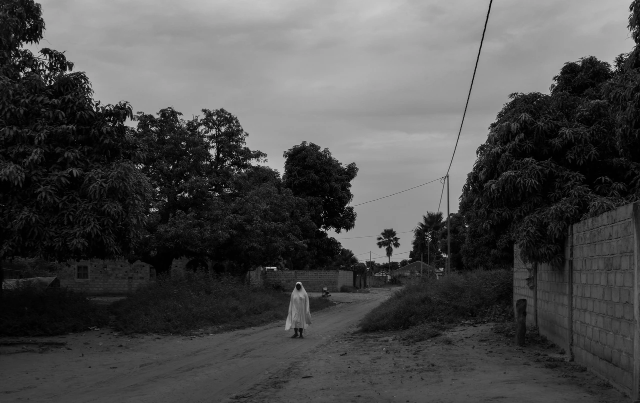 A lone figure in white on a quiet tree-lined street