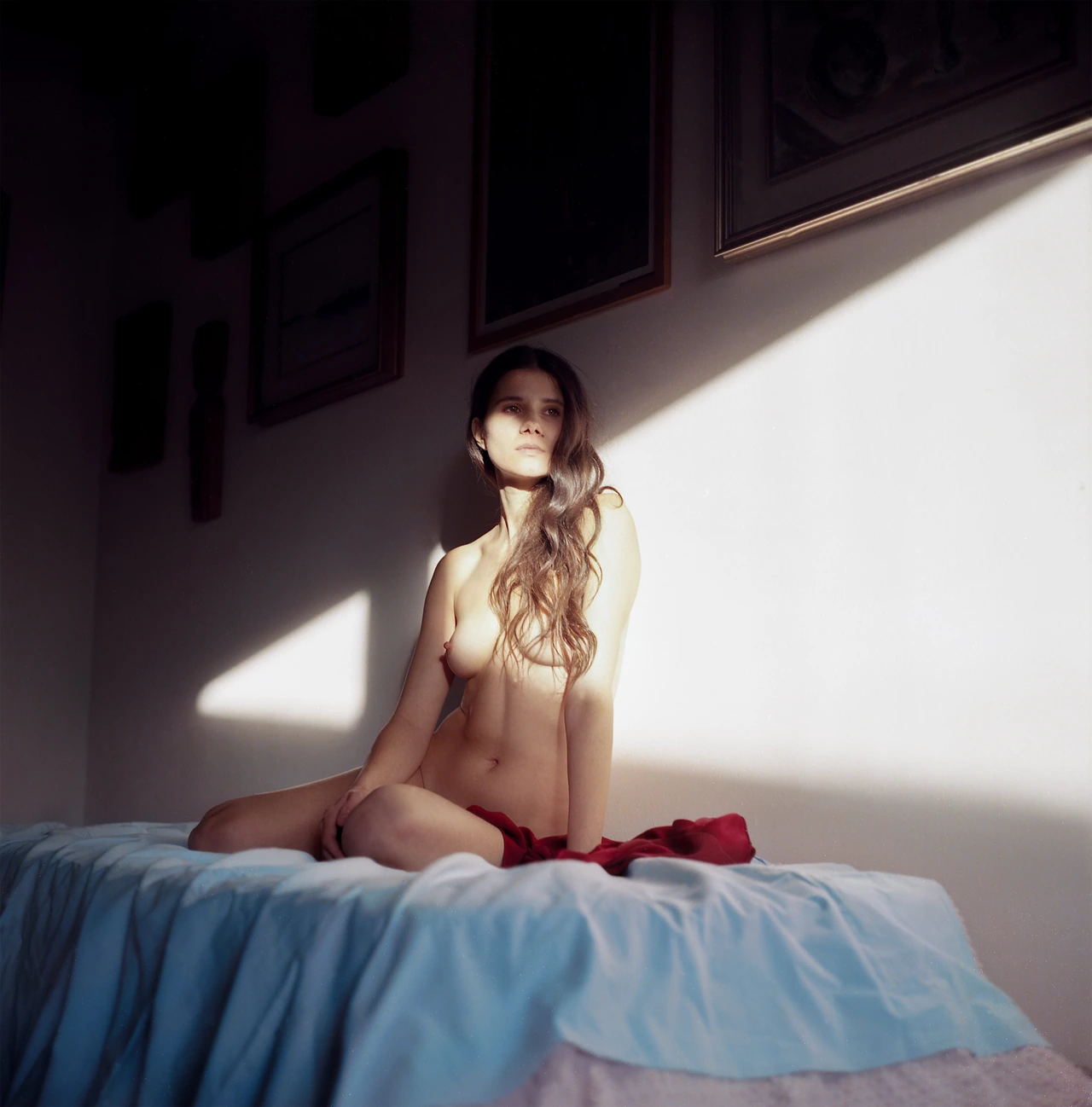 A seated figure crossed by sunlight in a quiet room