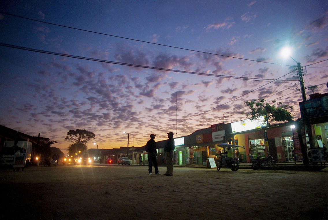 Two silhouettes on a street beneath a violet evening sky
